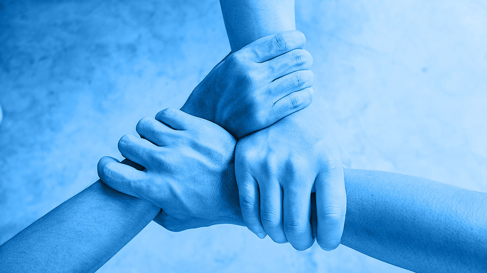 Röhm Symbolische Darstellung von Teamwork und Zusammenarbeit durch ineinandergreifende Hände Röhm Hände greifen ineinander – Symbol für Zusammenarbeit und Teamwork